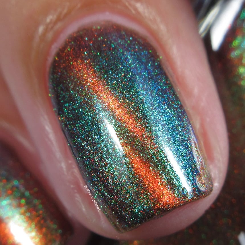 Magnetic holographic multichrome Cadillacquer nail polish in Once You See It, macro swatch on a single oval nail showing a vivid copper-orange magnetic cat-eye band arcing diagonally across a deep dark green-teal field with green-to-blue aurora shimmer scatter throughout, light skin tone, studio lighting, swatched by @_always_polished_
