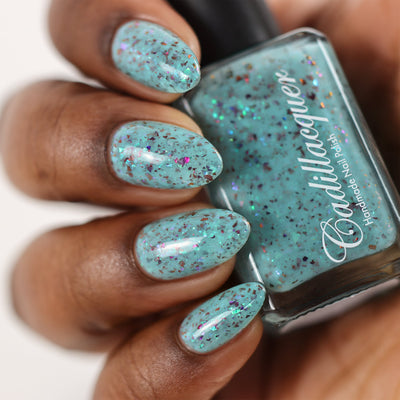 Cadillacquer Pastel Thoughts pastel teal purple chameleon iridescent crelly nail polish, bottle held with four-nail swatch, rich skin, studio lighting