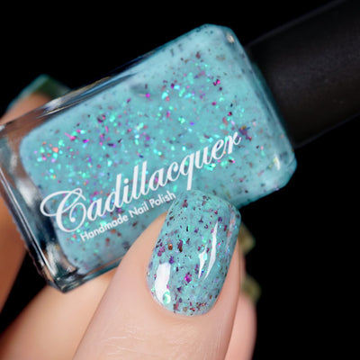 Cadillacquer Pastel Thoughts pastel teal purple chameleon iridescent crelly nail polish, bottle held with one-nail swatch, light skin, studio lighting