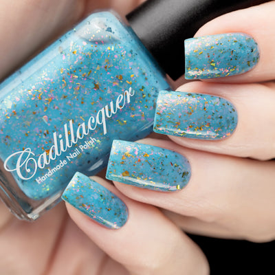 Cadillacquer Slow Mornings light blue gold chameleon iridescent crelly nail polish, bottle held with four-nail swatch, light skin, studio lighting