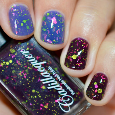 Thermal glitter and flake Cadillacquer nail polish in Strange Happenings, shown as bottle in hand with four swatched nails displaying cold blackened eggplant and warm dusty periwinkle-lavender thermal transition, loaded with neon yellow-green matte glitter in multiple sizes and large hot pink iridescent flakes, on light skin tone, studio lighting, swatched by @caitlinswatches