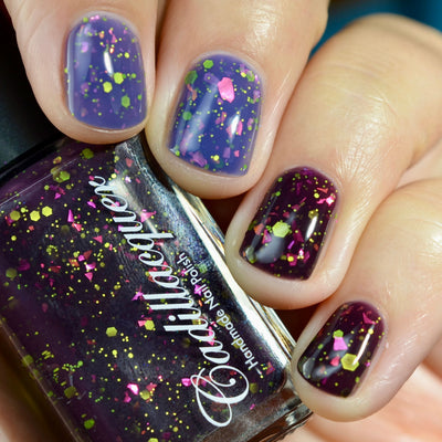 Thermal glitter-and-flake Cadillacquer nail polish in Strange Happenings, shown as a bottle held in hand alongside four swatched nails displaying both cold blackened eggplant and warm dusty blue-purple thermal states, loaded with neon yellow-green matte glitter in multiple sizes and hot pink iridescent flakes, on light-medium skin tone, studio lighting, swatched by @caitlinswatches