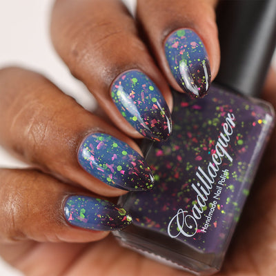 Thermal glitter and flake Cadillacquer nail polish in Strange Happenings, swatched on almond-shaped nails showing dusty blue warm state and blackened eggplant cold state transition with hot pink iridescent flakes and matte neon green glitter in multiple sizes, deep skin tone, studio lighting, swatched by @doseoflolade