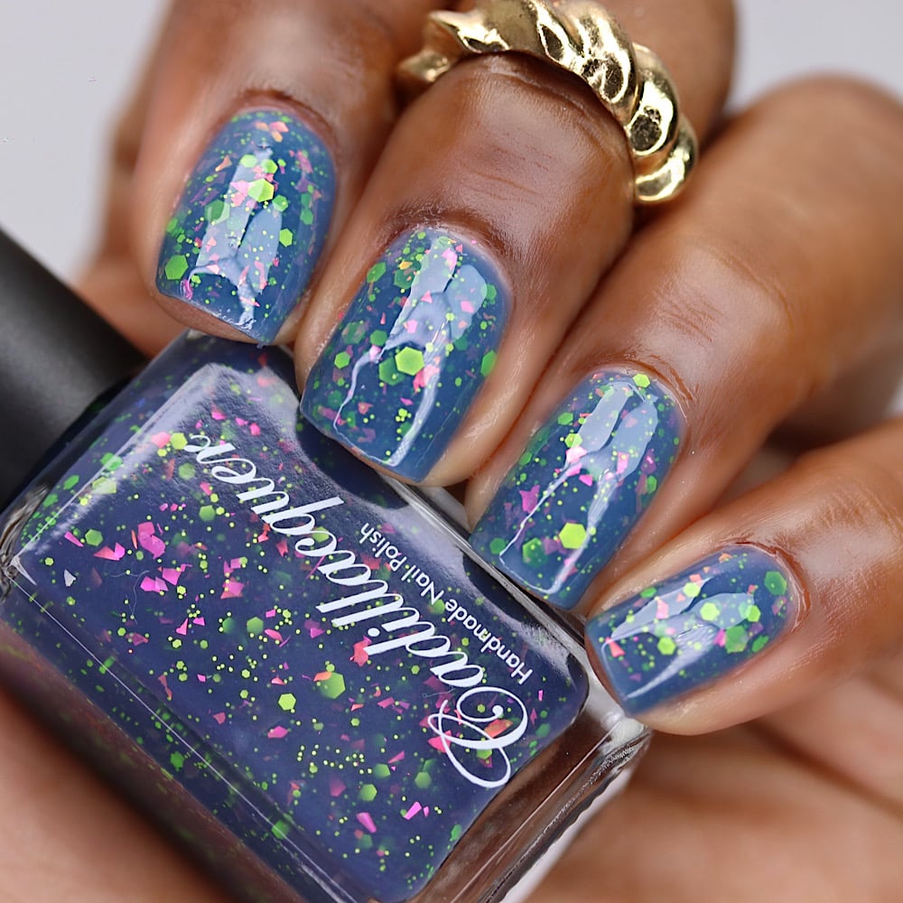 Thermal glitter-and-flake Cadillacquer nail polish in Strange Happenings, shown on eight squoval nails and held bottle, transitioning from blackened eggplant cold state to dusty periwinkle blue warm state, loaded with matte neon chartreuse green hexagon and micro glitter and neon pink iridescent flakes, on deep skin tone, studio lighting, swatched by @lacquer_is_life