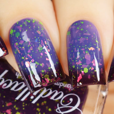 Thermal glitter-and-flake Cadillacquer nail polish in Strange Happenings, swatch on four oval nails showing a cold-to-warm gradient from blackened eggplant at the cuticle and tips to dusty periwinkle blue at the center, densely scattered with matte neon yellow-green glitter in hexagon and micro-dot sizes and large iridescent pink-to-purple-to-orange shifting flakes, light skin tone, studio lighting, swatched by @yyulia_m