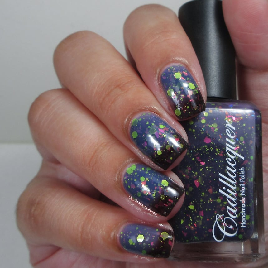 Thermal glitter-and-flake Cadillacquer nail polish in Strange Happenings, shown on eight short natural nails and in the bottle, transitioning from blackened eggplant at cool areas to dusty blue-violet at warm areas, scattered throughout with matte neon chartreuse-green hex and dot glitter in multiple sizes and hot pink iridescent flakes, on light skin tone, studio lighting, swatched by @_always_polished_