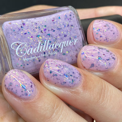 Cadillacquer Sweet Nothing pink teal chameleon iridescent crelly nail polish, bottle held with four-nail swatch, light skin, studio lighting
