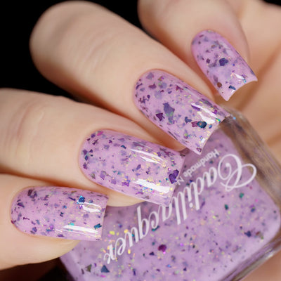 Cadillacquer Sweet Nothing pink teal chameleon iridescent crelly nail polish, bottle held with four-nail swatch, light skin, studio lighting