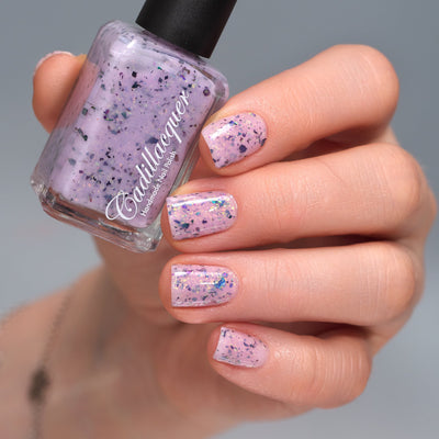 Cadillacquer Sweet Nothing pink teal chameleon iridescent crelly nail polish, bottle held with four-nail swatch, light skin, studio lighting