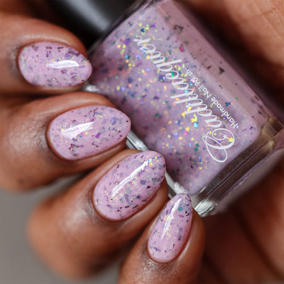 Cadillacquer Sweet Nothing pink teal chameleon iridescent crelly nail polish, bottle held with four-nail swatch, deep skin, studio lighting