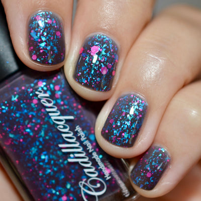 Thermal glitter-and-flake Cadillacquer nail polish in What Lurks Within, shown on five short natural nails on light-medium skin with a matching bottle, cold state reveals a blackened eggplant base, warm state shifts to blueish grey, loaded throughout with large iridescent teal flakes that shift blue-to-green and matte neon pink glitter in mixed sizes, studio lighting, swatched by @caitlinswatches