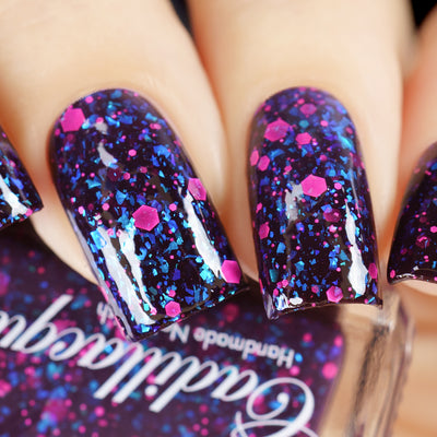 Thermal glitter-and-flake Cadillacquer nail polish in What Lurks Within, shown as a swatch on five squoval nails in the cold state, a near-black eggplant-purple base loaded with cyan-to-cobalt iridescent flakes and matte neon-pink hexagonal and micro glitter, on light skin tones, studio lighting, swatched by @yyulia_m