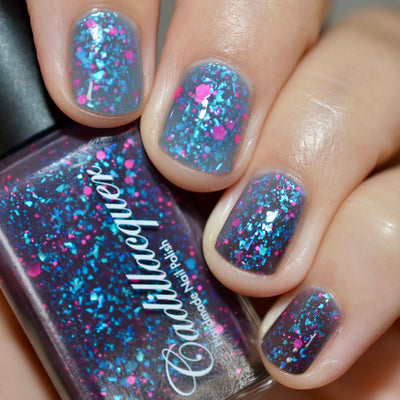 Thermal glitter and iridescent flake Cadillacquer nail polish in What Lurks Within, shown on five short squoval nails transitioning from blackened eggplant cold state to cool blue-grey warm state, packed with cyan-teal iridescent flakes and neon hot pink matte glitter, with matching bottle held in hand, light skin tone, direct flash lighting, swatched by @caitlinswatches