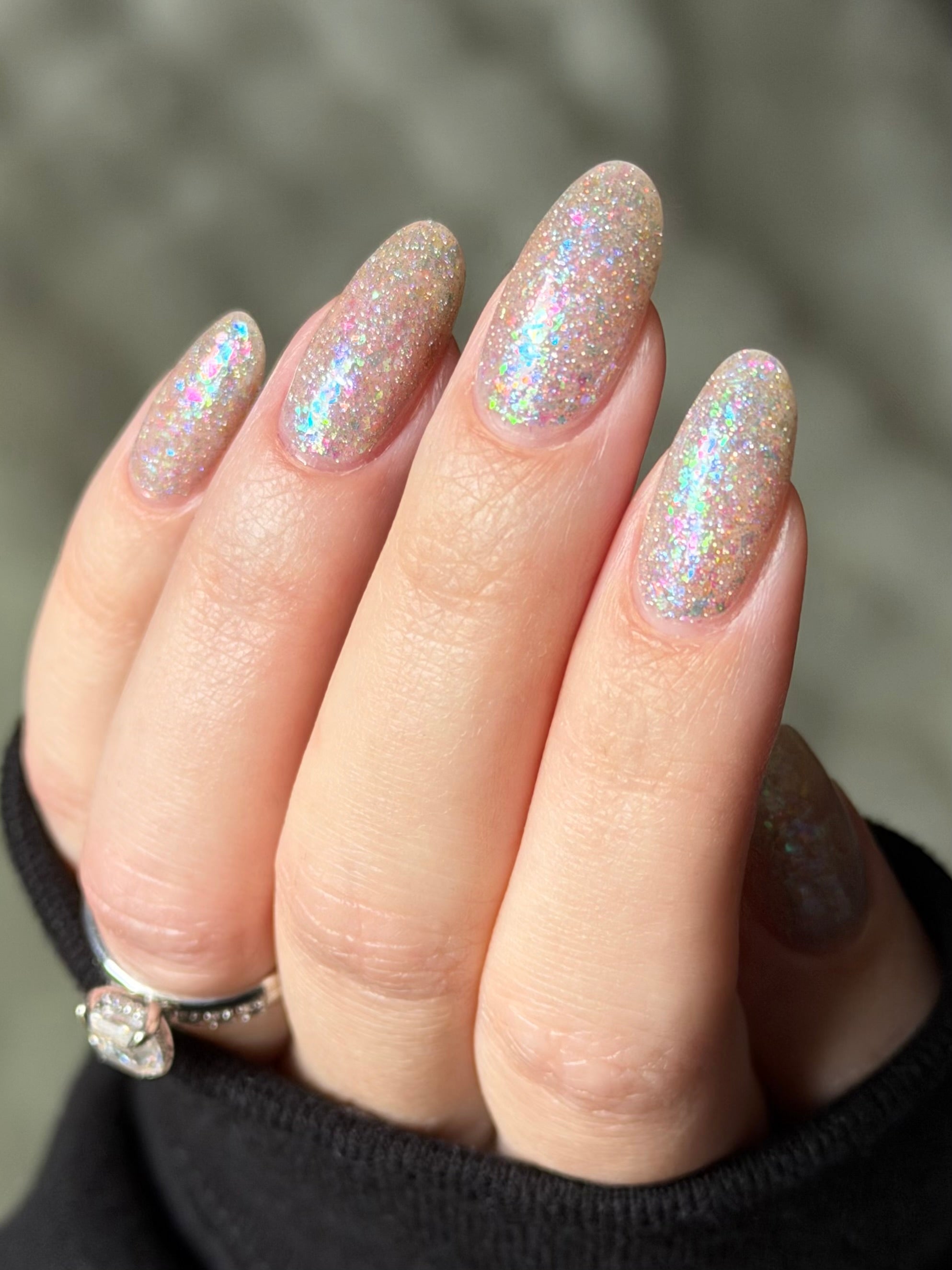 Be Gay, Do Crime by Glitch Lacquer, silver holo glitter and rainbow flake topper over sheer nude, on light skin tone nails