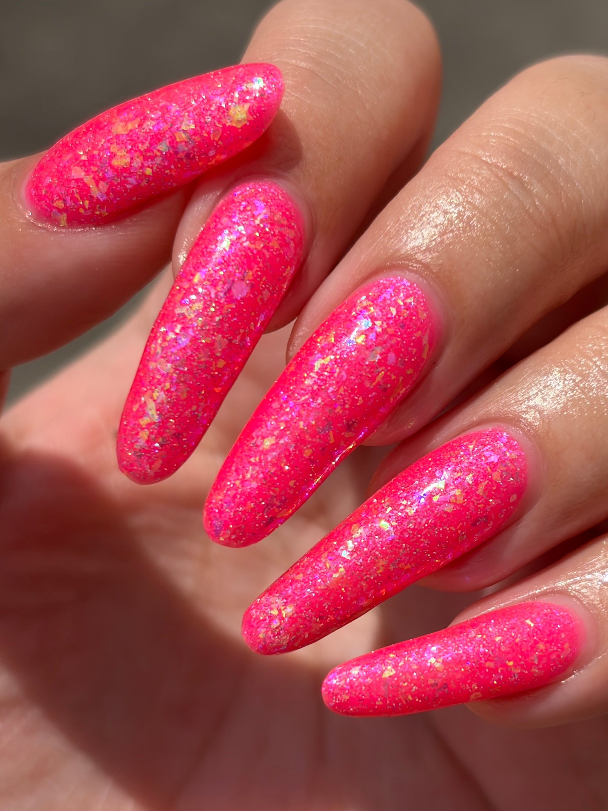 Be Gay, Do Crime by Glitch Lacquer, holo glitter and rainbow flake topper over neon pink, on light-medium skin tone nails