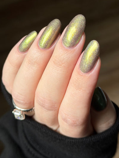 Safe House Glow by Glitch Lacquer, grey base, gold-to-teal multichrome shift, holo shimmer, on light skin tone almond nails