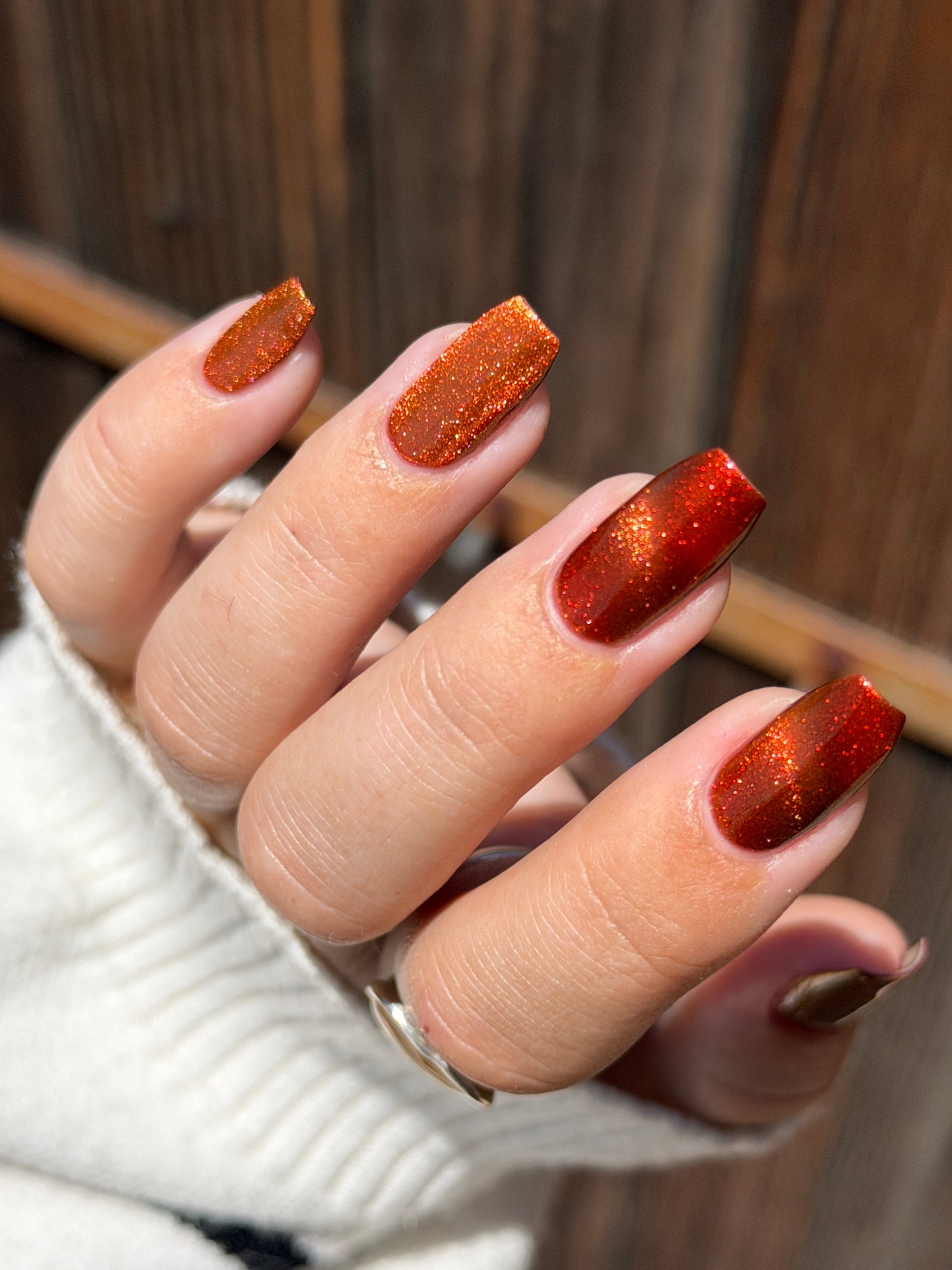 Marigold by Glitch Lacquer, burnt orange jelly with red shimmer and orange-to-gold magnetic shift, light skin tone nails