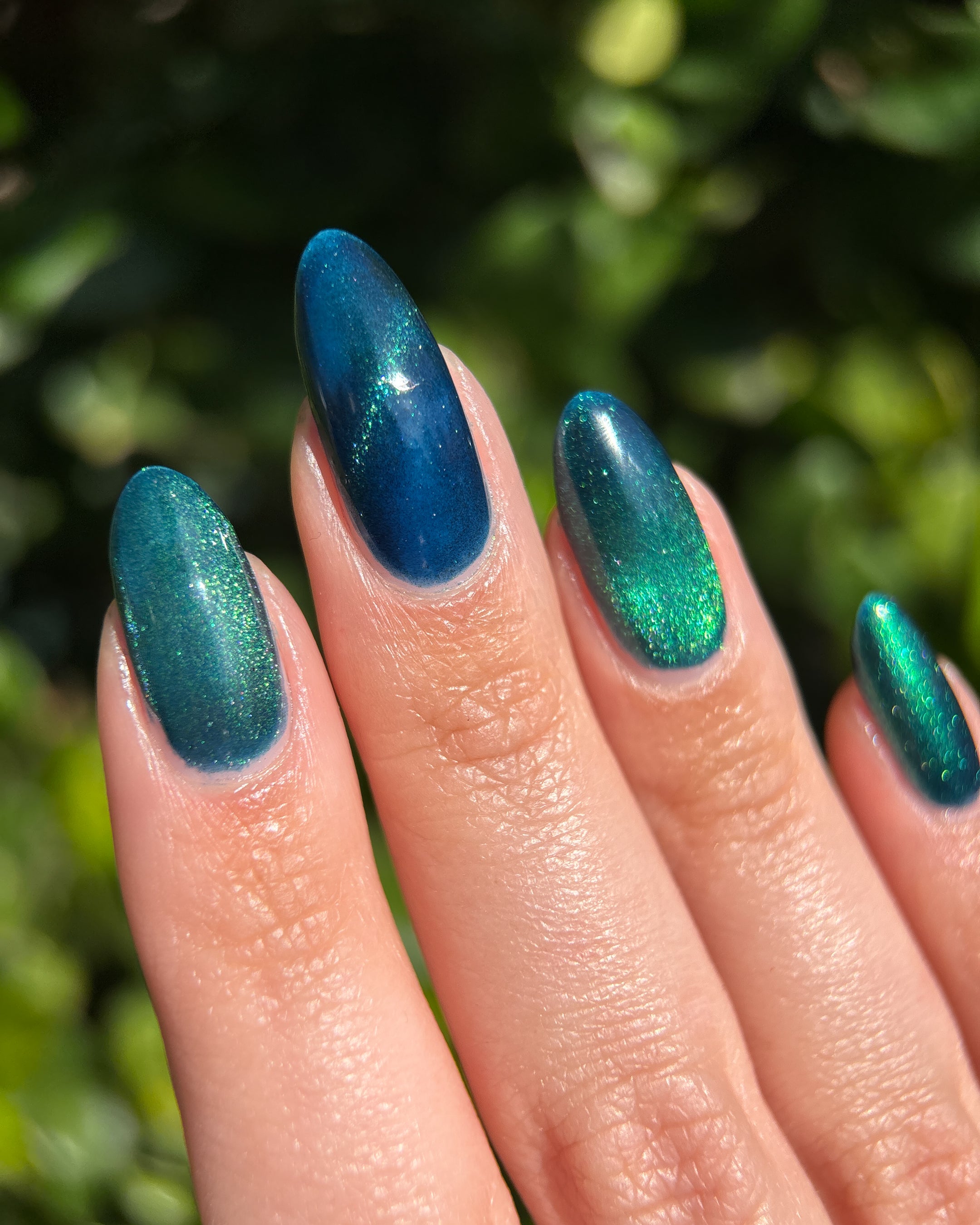 Do-Nuts by Glitch Lacquer, deep blue jelly, green-to-teal-to-blue magnetic, on light skin tone almond nails