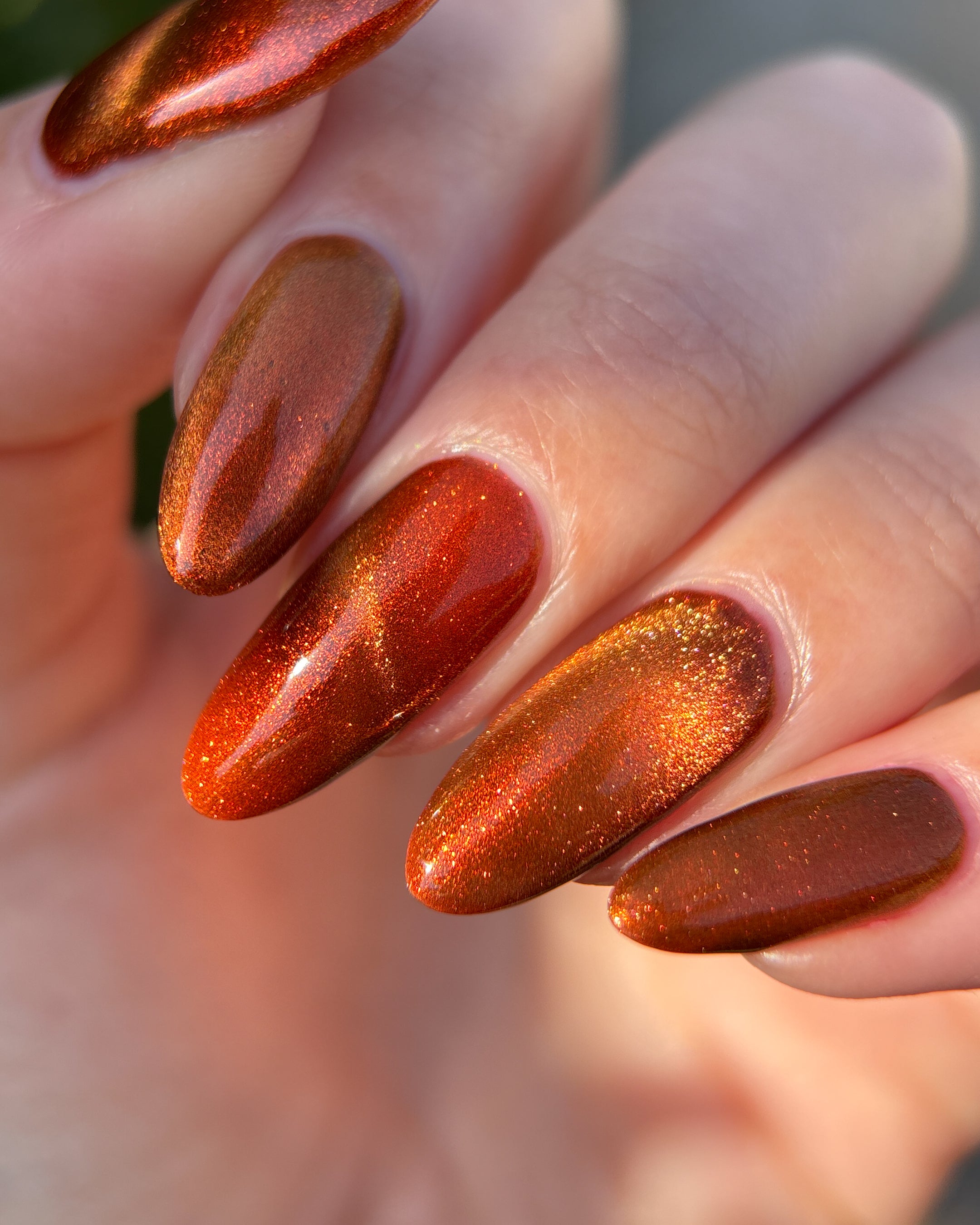 Marigold by Glitch Lacquer, burnt orange jelly, orange-to-gold magnetic cat-eye, on light skin tone almond nails