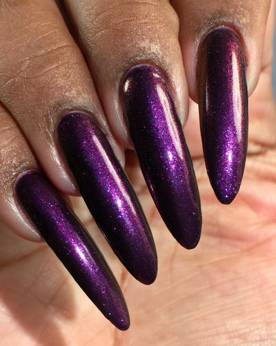 Sister Outsider by Glitch Lacquer, blackened purple jelly with magenta-purple sparkle, on deep skin tone stiletto nails